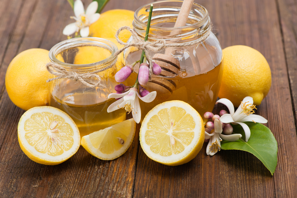 Jars,Of,Honey,And,Lemons,With,Flowers,On,Wooden,Table